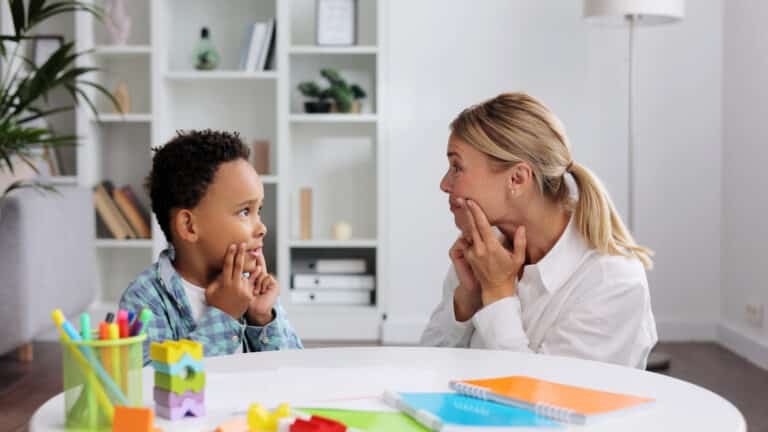 Therapist and child sitting together practicing speech exercises