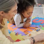 child and therapist doing a puzzle on the ground