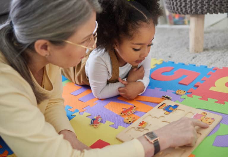 child and therapist doing a puzzle on the ground