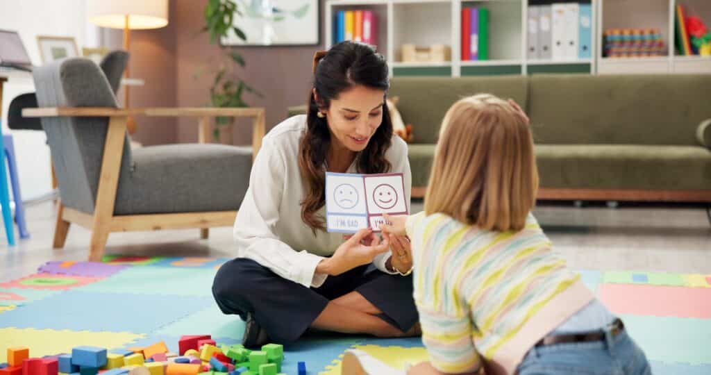child therapist and child sitting on the floor with emotion flash cards