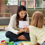 child therapist and child sitting on the floor with emotion flash cards