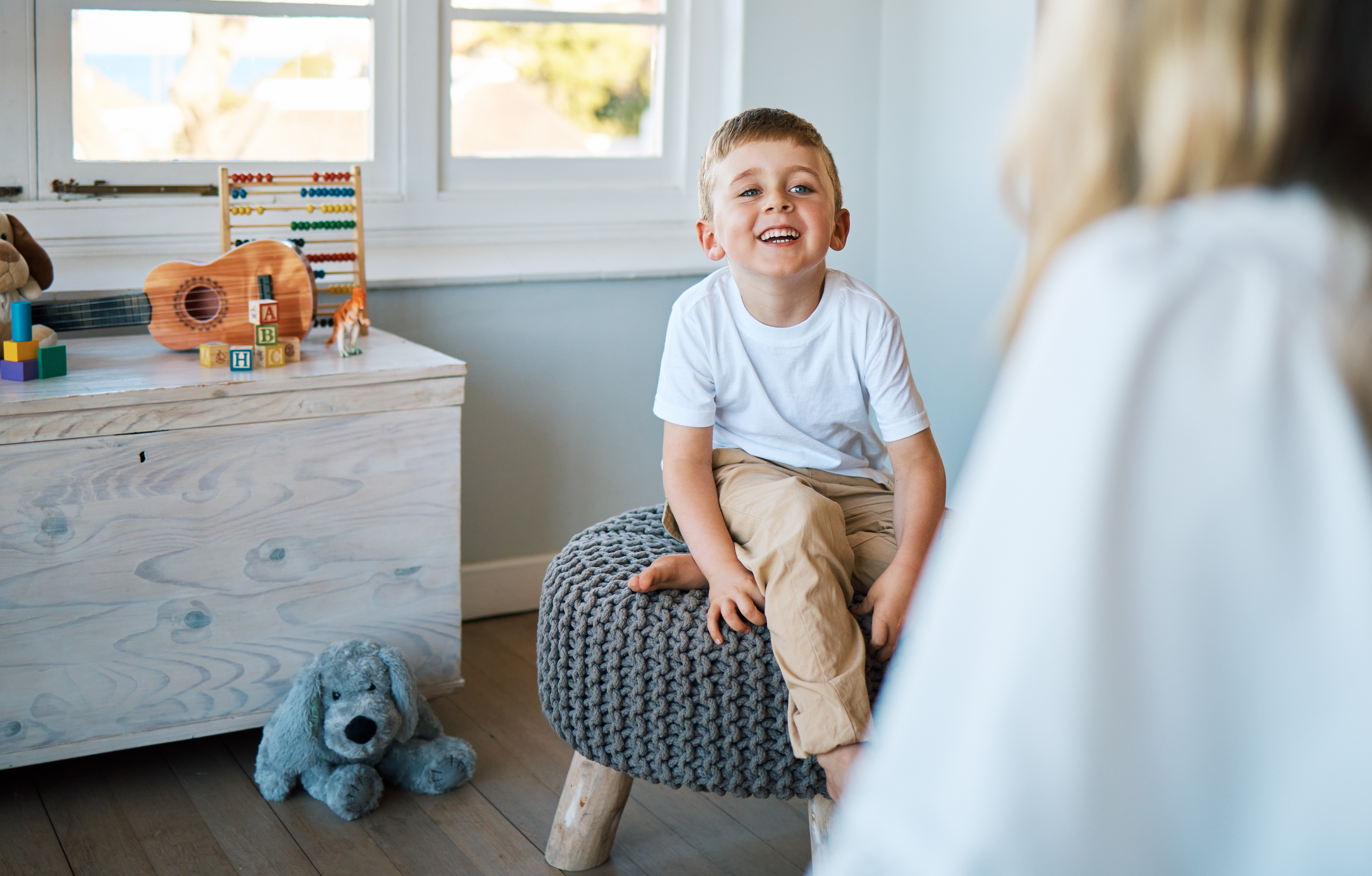 child sitting on a chair smiling at therapist